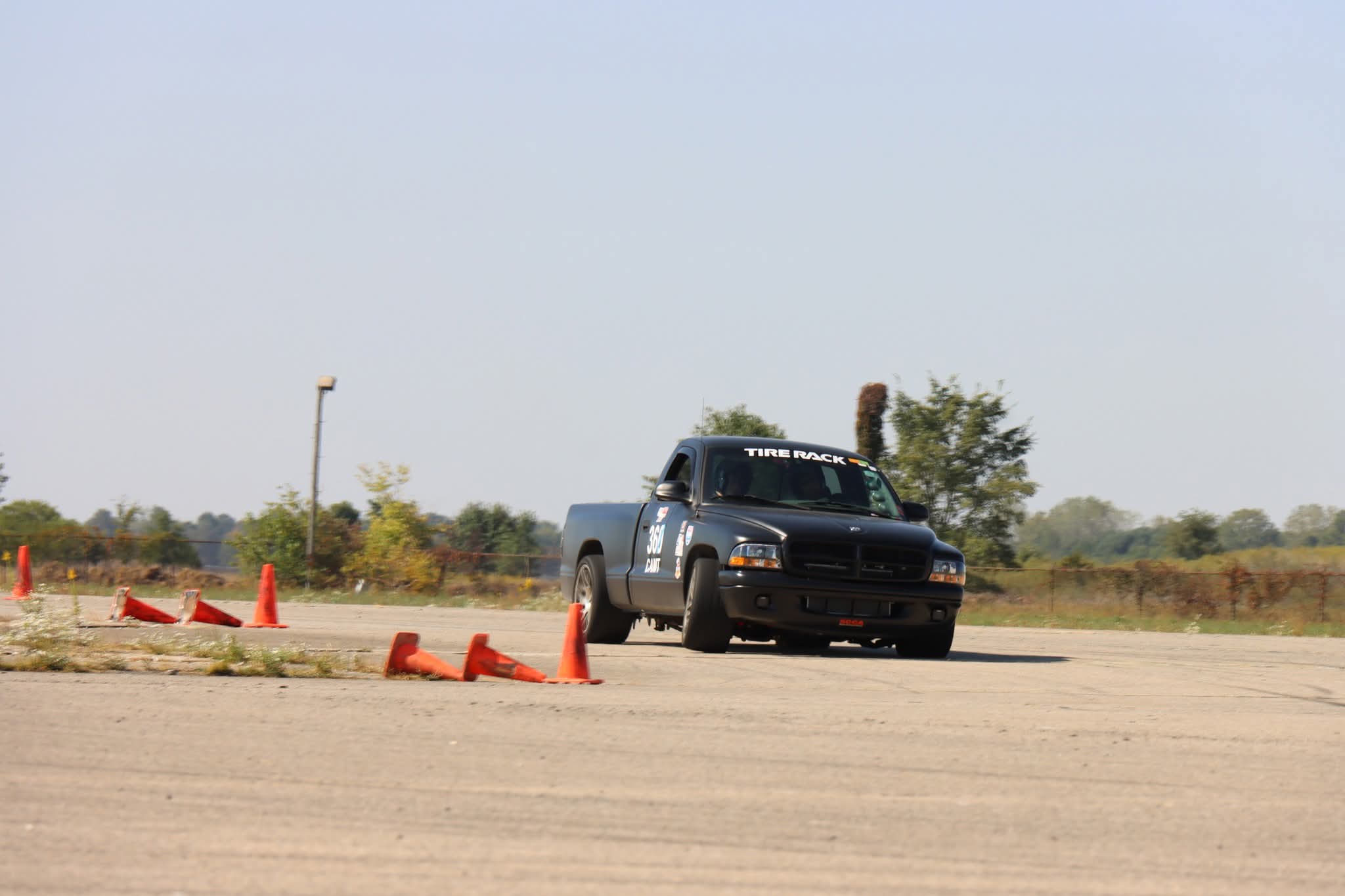 Black Dodge Dakota pickup truck number 360 navigating an orange cone course at an SCCA autocross event on an open tarmac surface