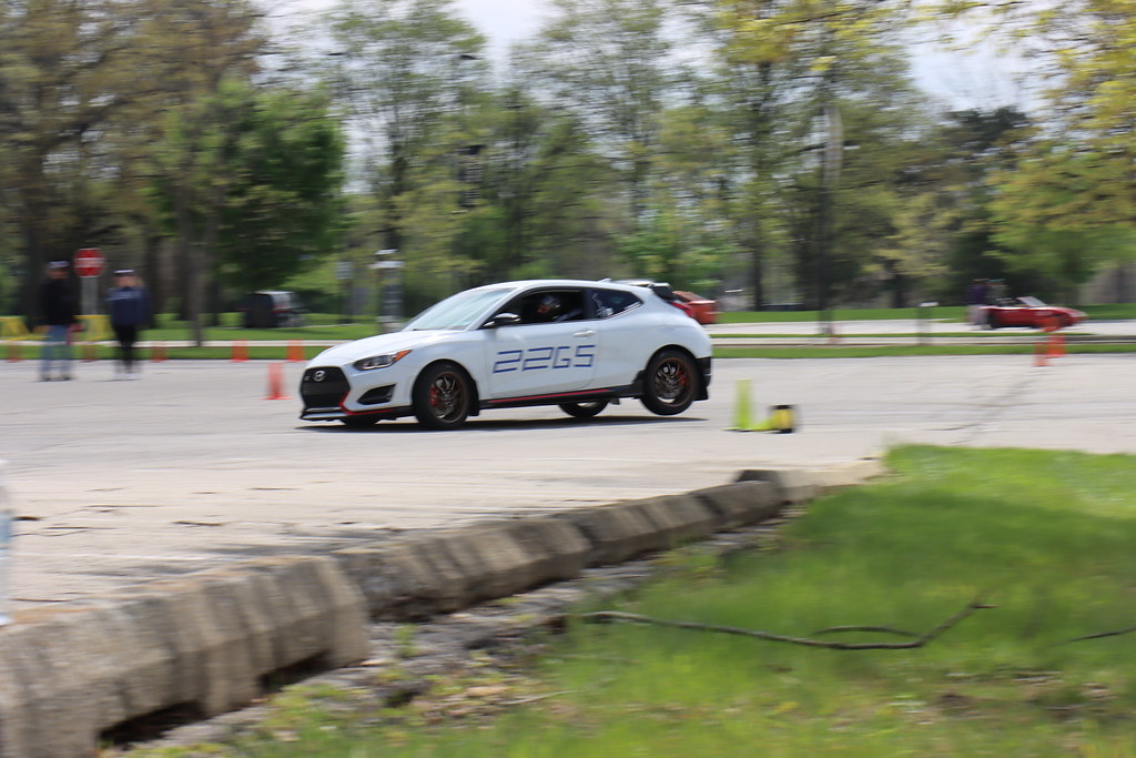 White Hyundai Veloster N with number 22GS navigating an SCCA autocross course marked by orange and green cones